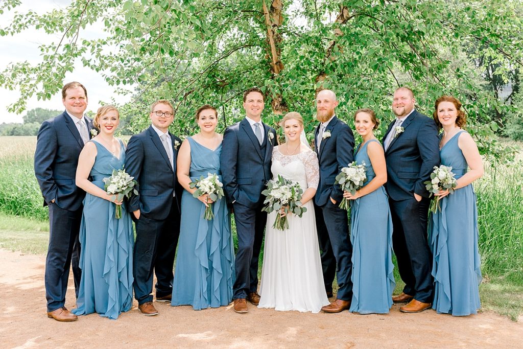 Formal bridal party portrait bridesmaids in blue dresses groomsmen in navy suits