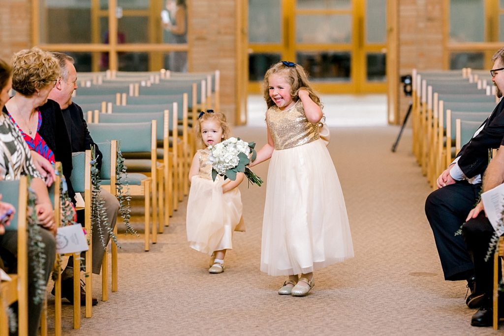 flower girls walking down the aisle in pink and gold dress at St. Andrew Lutheran Church in Minnesota