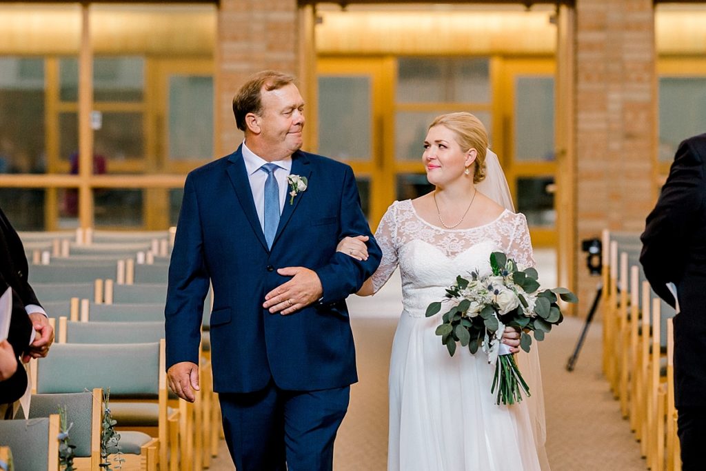 bride walking down the aisle with father cute at St. Andrew Lutheran Church in Minnesota