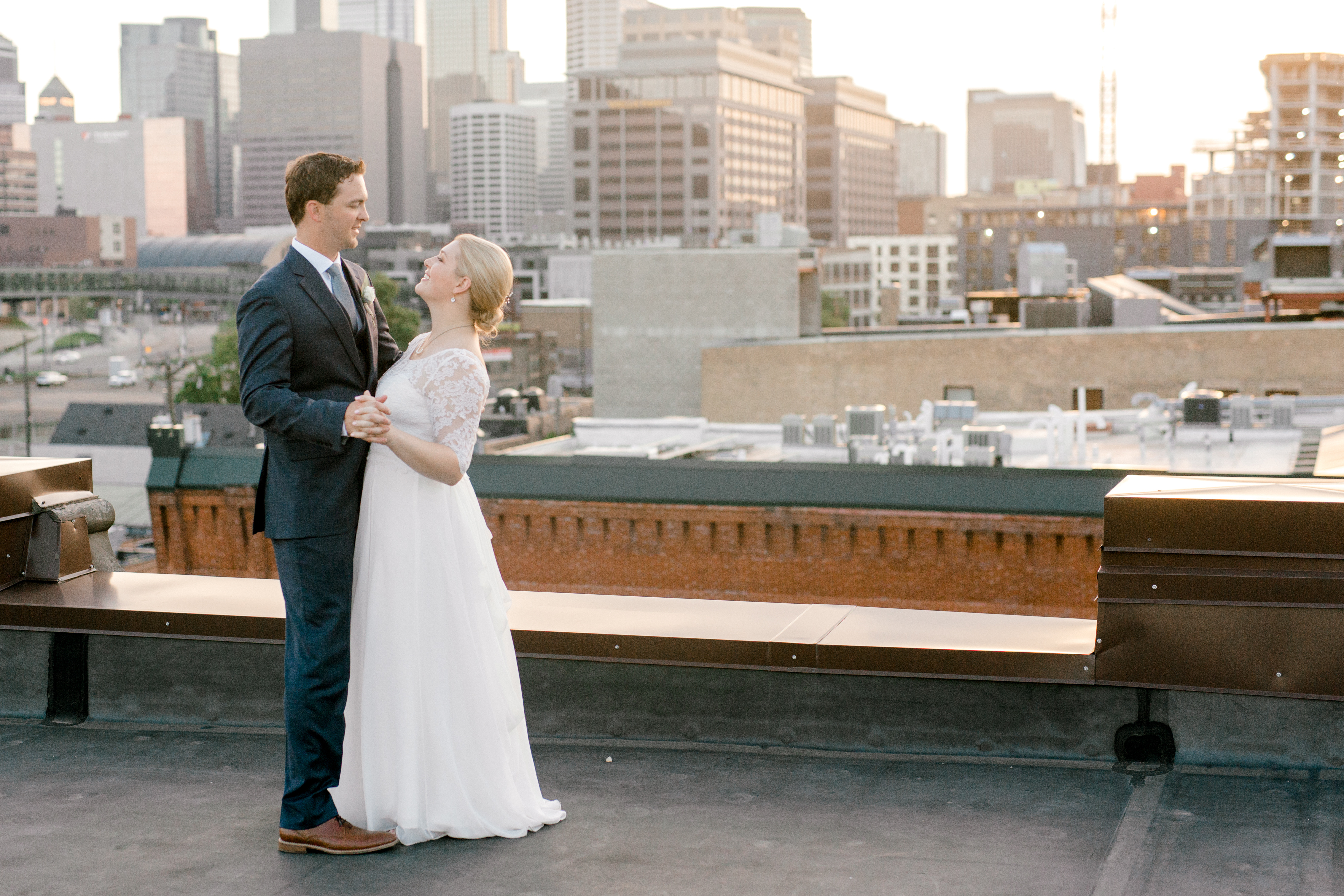 bride and groom dancing on downtown minneapolis rooftop at sunset