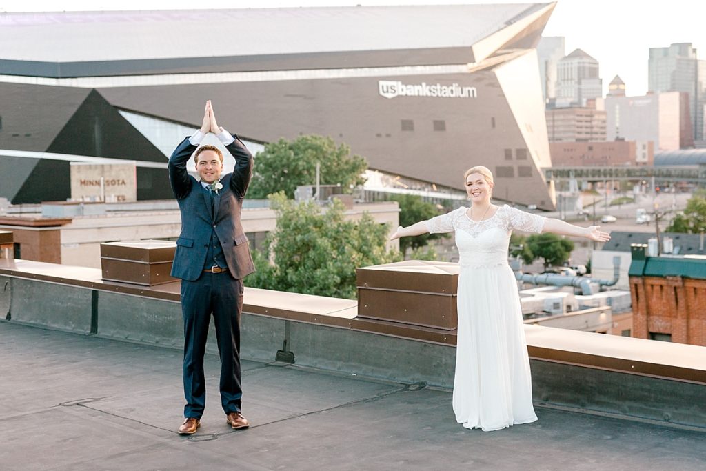 wedding pictures on day block event center rooftop in front of minneapolis downtown skyline with US Bank Stadium Vikings behind them