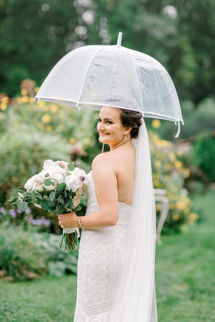 Bridal portrait with clear umbrellas on rainy day wedding