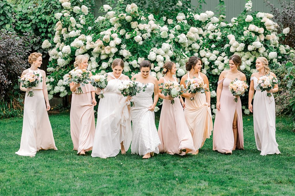 Picture of bridesmaids walking at in front of flower bush